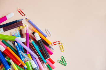 Colored pencils, markers and paper clips many colors of the rainbow for business and office. Office supplies lie mixed up on a light table.