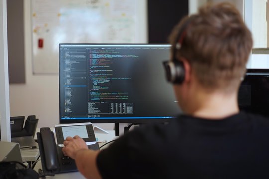 Real male web programmer coding javascript, php, symfony, react at work 