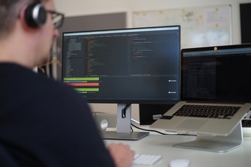 Real male web programmer coding javascript, php, symfony, react at work 