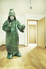 Ugly man in empty apartment dressed to protective suit and mask