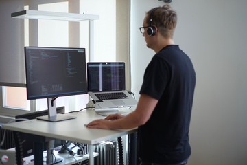 Real male web programmer coding javascript, php, symfony, react at work 