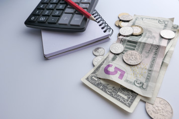 close up of stack of coin, cash and wallet on table.