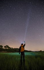 Persona con linterna mirando las estrellas del cielo por la noche.