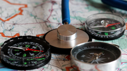 Blue stethoscope and three compasses on the map