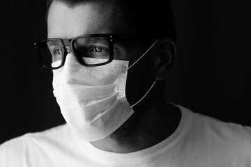 Close-up shot. Man in spectacles and medical mask,  black and white portrait. .