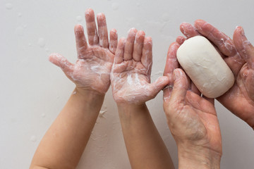 Top view of soaped child and woman hands holding soap on the white background