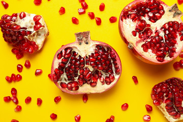Pomegranate and seeds on yellow background, top view