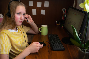 Teenager girl with black headphones for remote learning via a computer from home room. Distance learning online education. 