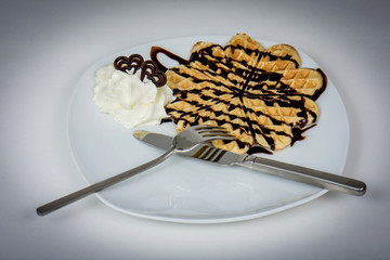 Fototapeta premium Waffles with chocolate and cream for a tasty desert.