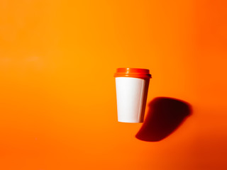 White paper cup drops on an orange background.
