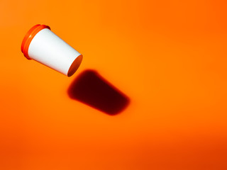 White paper cup drops on an orange background.