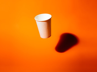 White paper cup drops on an orange background.