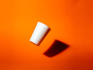 White paper cup drops on an orange background.