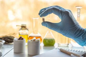 Hand of a pharmacist holds a capsule with dietary supplements