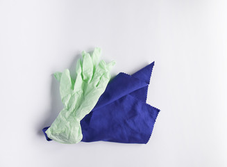 Rubber gloves and microfiber cloth for cleaning on light background