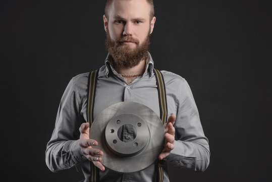 Handsome young man presents car parts on a gray background. The concept of sales and testing of goods