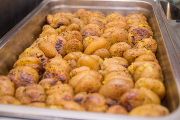 Golden roasted potatoes in skin in a hot catering baking food tray