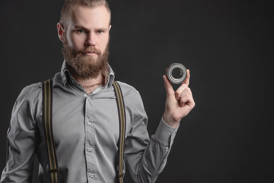 Handsome young man presents car parts on a gray background. The concept of sales and testing of goods