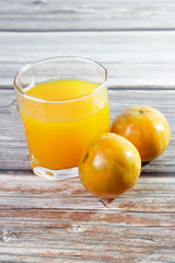 Glass of fresh orange juice on wooden background