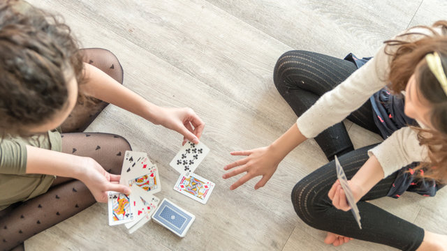 Enfants jouant aux cartes assise sur du parquet
