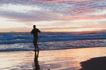 Chico joven haciendo disfrutando de la playa al atardecer