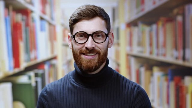 Close-up portrait handsome young european man student or librarian smiling joyfully at camera enjoying work at library. Real people. Job, education concept.
