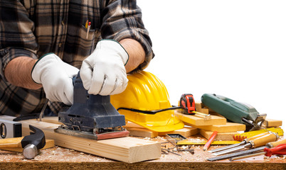 Close-up. Carpenter with his hands protected by gloves with the electric sander smoothes a wooden...