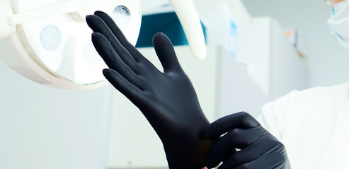 The doctor puts on medical gloves. The doctor in the operating room. Styling conditions in a medical office, operating room, treatment room, dentistry