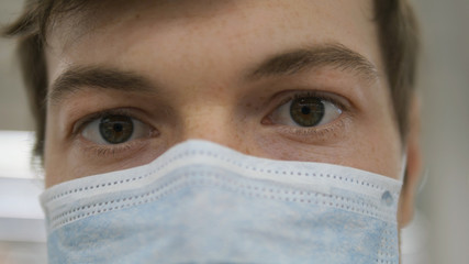 doctor in medical mask looks at camera extremely close-up, pandemic covid-19