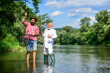 Fototapeta premium Weekend with family. happy fishermen friendship. fly fish hobby of businessman. retirement fishery. Two male friends fishing together. Catching and fishing concept. retired dad and mature bearded son