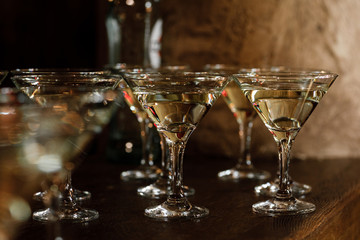 Martini glasses stand on a wooden stand. Martini glasses are on the bar. clean glasses with alcohol. selective focus