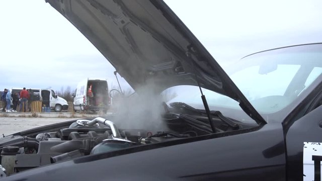 The sports car broke down, smokes from under the hood, the driver shocked.