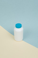 White plastic medical container for tablets or capsules on a yellow-blue background