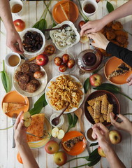Festive easter meal on a wooden table with home baking. Meeting with friends who have healthy, natural foods. Flat lay of a table with people hands.