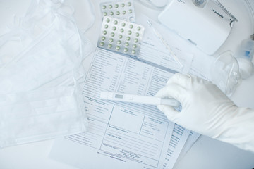 Naklejka na ściany i meble hand in gloves with a virus test on a background of a desktop in a hospital. coronovirus test in the laboratory, light background