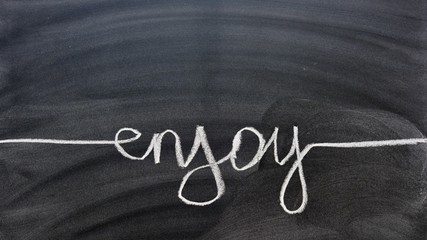 la palabra enjoy escrita en inglés, con una tiza en la pizarra © KukiLadrondeGuevara