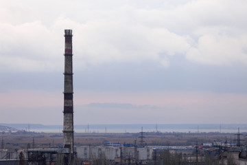 Obraz premium Industrial zone with a high chimney for the removal of smoke on the background of the lake.
