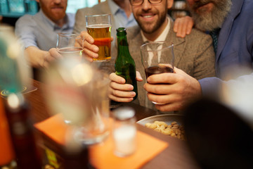 Close-up of group of men drinking beer from the bottles and glasses at the bar counter