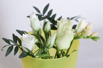 Mini bouquet of eustoma, freesia flowers and eucalyptus branches in a glass.