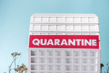 carton hospital model with quarantine lettering isolated on blue