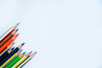 A row of bunch of different colored wood pencil crayons on a white background