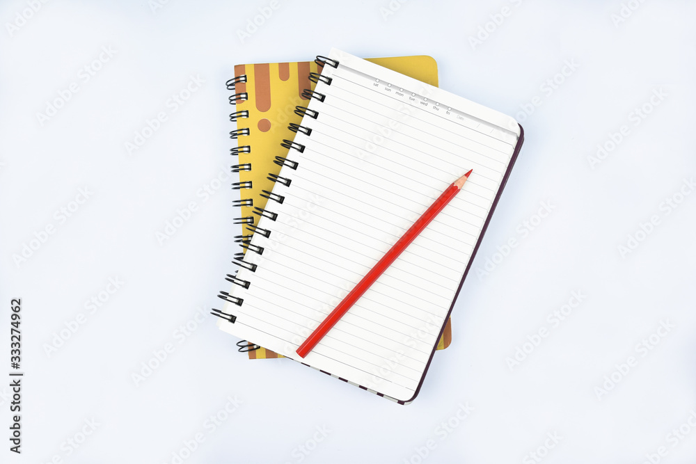 Sticker two diaries before a paper background with a red wood pencil top of one of them