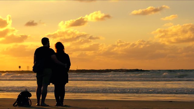 Couple look at the sea on a sunset