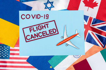 top view of blue envelope with covid-19 and flight canceled lettering near toy plane on different flags