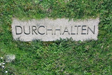 The word - DURCHHALTEN -  on a memorial stone is a German term and means: KEEP OUT. Coronavirus, COVID-19,  it's a disaster.
