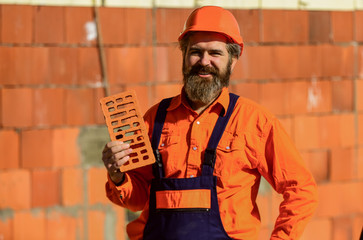 Element in masonry construction. Builder hold brick. Bearded man wear hard hat at construction...
