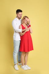 Man with engagement ring making marriage proposal to girlfriend on yellow background