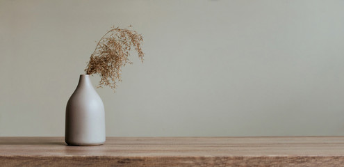 Dry reed in modern vase on the wooden table indoor