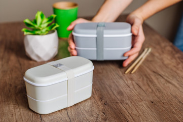 Female hands holding one lunch box on the background