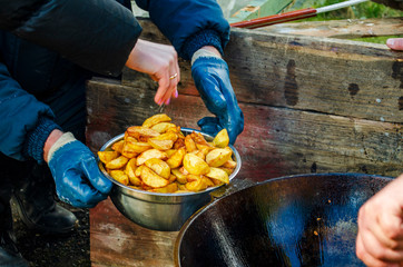 hands establish fried potatoes in a cauldron steam goes and boils oil